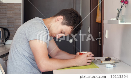 man traveler with a cup of tea sitting and falling asleep at small kitchen 59115294