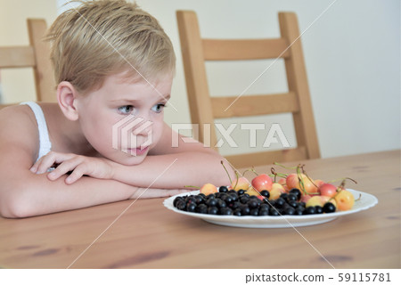 the child is sad in front of a plate of berries. allergy. disease. loss of appetite. 59115781
