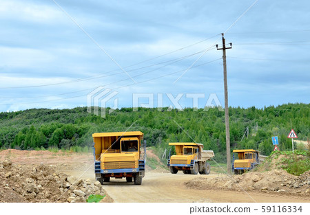 Big yellow dump trucks working in the limestone open-pit. 59116334