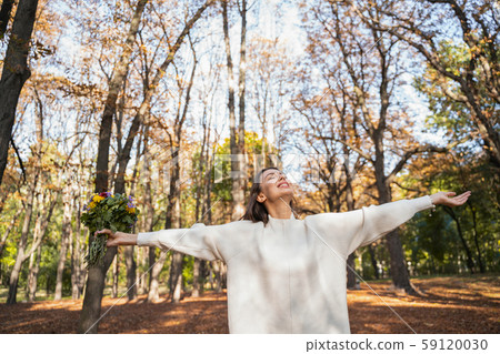 Cheerful woman loving autumn nature in the park Cheerful woman loving autumn nature in the park 59120030