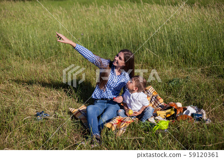 beautiful woman with her son on a picnic in a field near the forest 59120361
