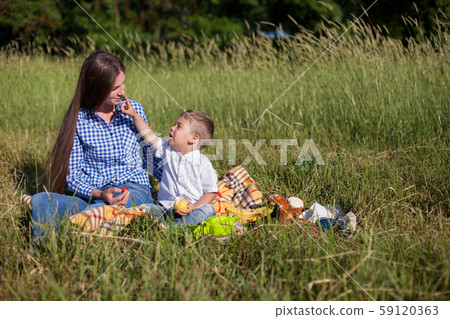 beautiful woman with her son on a picnic in a field near the forest beautiful woman with her son on a picnic in a field near the forest 59120363