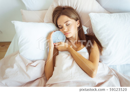 Close up of cute girl that embracing her alarm-clock 59123520