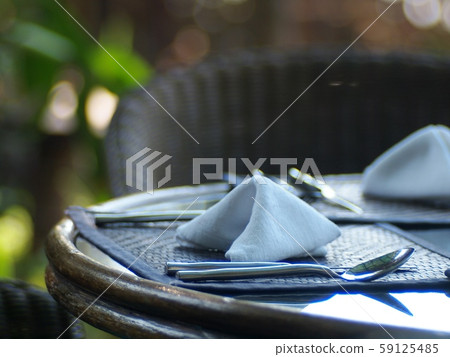 stainless steel silver colour fork & spoon on wooden table top with hand crafted decoration mat prepare for guest in vintage style garden restaurant under natural lighting warm welcome mood background 59125485