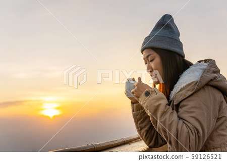 An Asian woman sits coffee at sunrise on the top 59126521