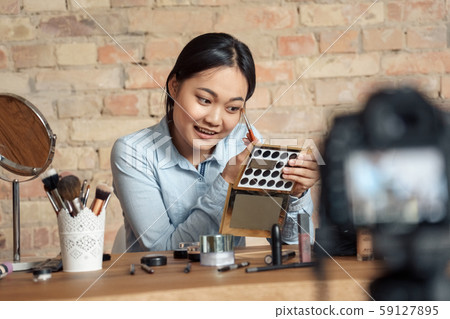 Young adult asian girl making visage and recording video on modern camera 59127895