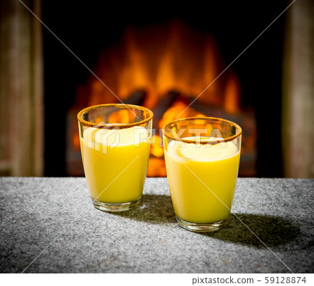 Two eggnog glasses at the fireplace 59128874