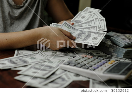 Hand holding smartphone and calculator on a stack of 100 US dollars banknotes lots of money 59132912