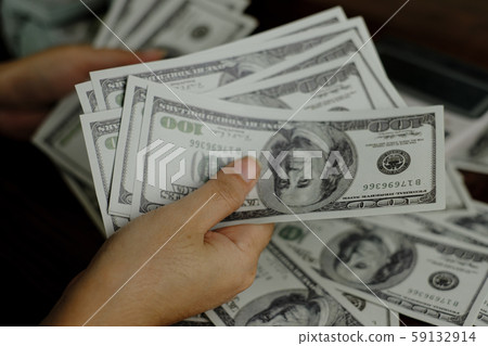 Hand holding smartphone and calculator on a stack of 100 US dollars banknotes lots of money Hand holding smartphone and calculator on a stack of 100 US dollars banknotes lots of money 59132914