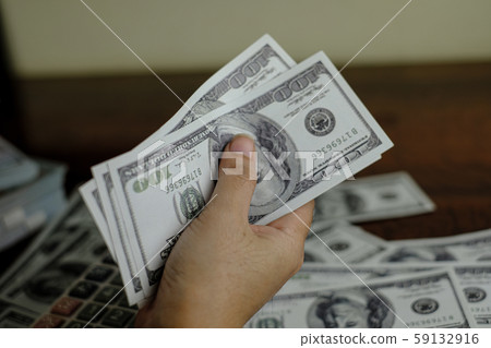 Hand holding smartphone and calculator on a stack of 100 US dollars banknotes lots of money Hand holding smartphone and calculator on a stack of 100 US dollars banknotes lots of money 59132916