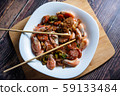 Cooked tasty dish fried shrimp with vegetables in sweet and sour sauce. Carrots, broccoli, cauliflower, shrimp are on a white plate. 59133484