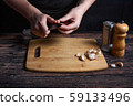 Chef at work. Cook's hands are tearing a knife over garlic. Preparing the ingredients for the future dish. Dark background 59133496