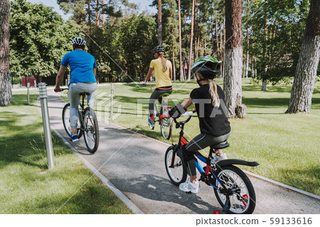 Little girl and her parents riding bicycles outdoors 59133616