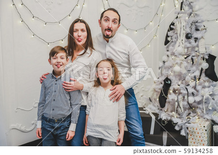 Portrait of happy family members: mother, father, son, daughter on white background near christmas Portrait of happy family members: mother, father, son, daughter on white background near christmas 59134258