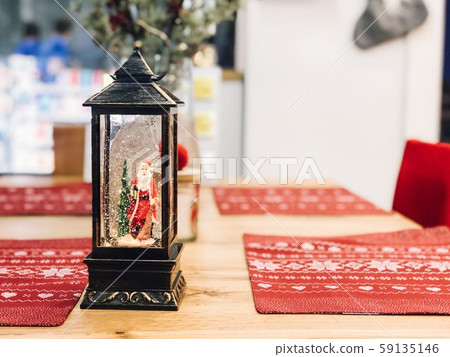 Christmas table with red decorated cloth and lamp with snow and Santa. Copy space Christmas table with red decorated cloth and lamp with snow and Santa. Copy space 59135146