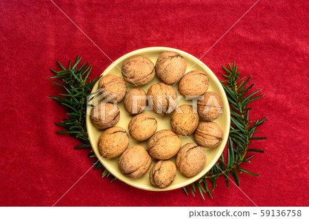 Walnuts in a plate on a red background. 59136758