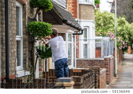 Man attaches house number to wall Man attaches house number to wall 59136849