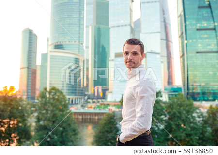 Businessman looking on copy space while standing against glass skyscraper Businessman looking on copy space while standing against glass skyscraper 59136850