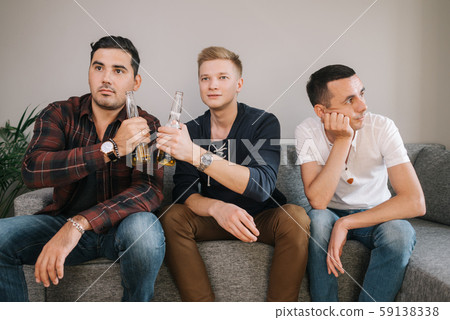 Two friends are clinking beer bottles after a goal from their football team 59138338