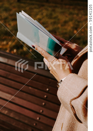 Woman in an autumn coat holds a book. Autumn park 59141105