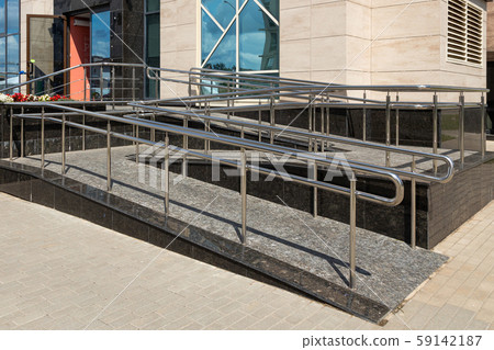 Wheelchair ramp of two uneven horizontal surfaces, street view, window with sky reflection 59142187