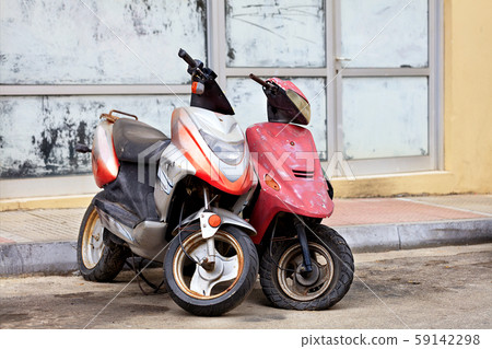 Two old worn mopeds stand alone at the edge 59142298