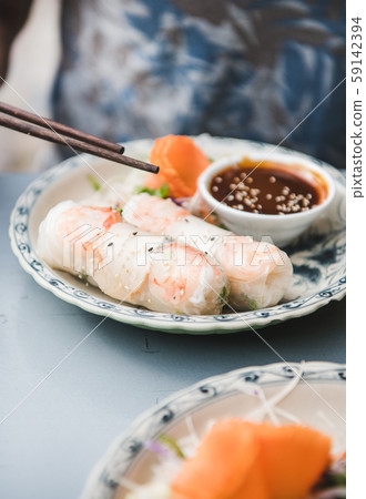 Man eating rice paper summer rolls with 59142394