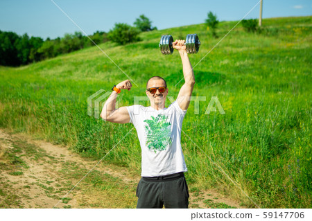 Handsome man with dumbbell in one hand show biceps Handsome man with dumbbell in one hand show biceps 59147706