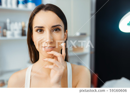 Patient shows cream on finger, cosmetician office Patient shows cream on finger, cosmetician office 59160606