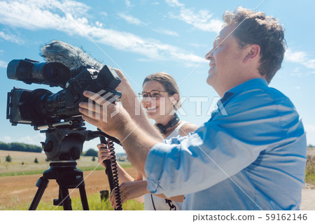 Cameraman with his camera and assistant working in production Cameraman with his camera and assistant working in production 59162146