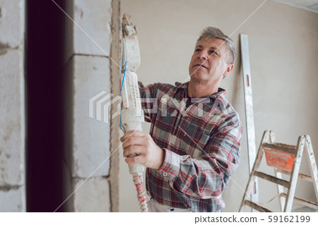 Plasterer smoothing interior wall with machine 59162199