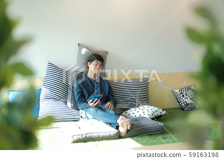 asian teenager man listening to music from smart mobile phone while sitting on floor at home asian teenager man listening to music from smart mobile phone while sitting on floor at home 59163198