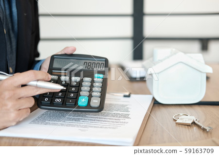realtor agent with house model showing price number on calculator. buying renting property. real estate insurance. realtor agent with house model showing price number on calculator. buying renting property. real estate insurance. 59163709