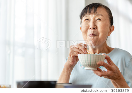 Senior woman eating rice in a bowl 59163879