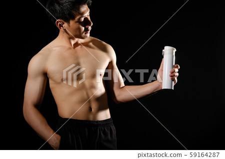 athletic muscular bodybuilder man with naked torso six pack abs holding protein drink. fitness workout concept athletic muscular bodybuilder man with naked torso six pack abs holding protein drink. fitness workout concept 59164287