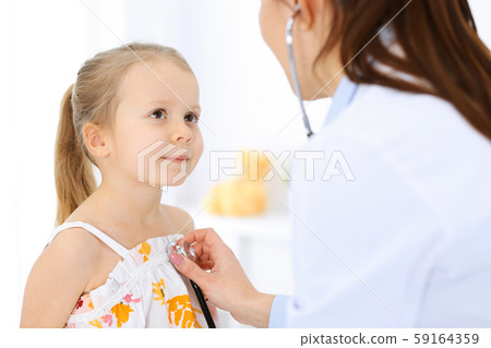 Doctor examining a little girl by stethoscope. Happy smiling child patient at usual medical Doctor examining a little girl by stethoscope. Happy smiling child patient at usual medical 59164359