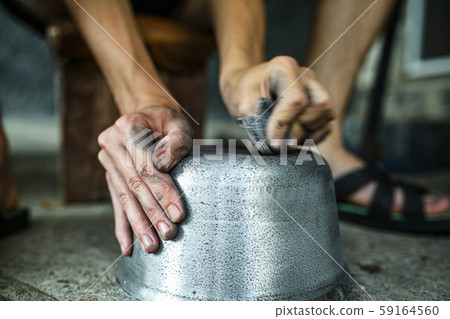 boy cleans the iron pan with his hands 59164560