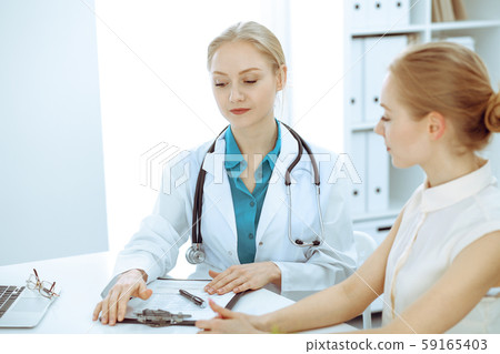 Doctor and patient talking in hospital office while sitting at the desk. Health care and client 59165403