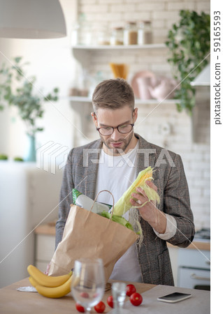 Man taking corn out of bag after going to supermarket Man taking corn out of bag after going to supermarket 59165593