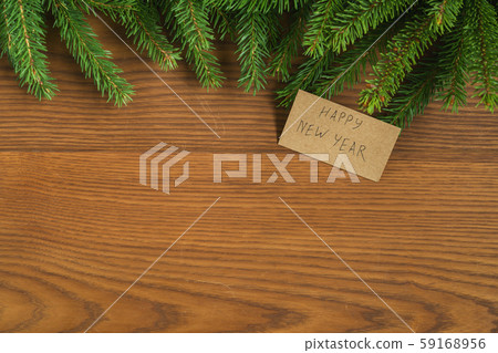 Flat lay christmas background with spruce twigs and happy new year card on ash wood surface Flat lay christmas background with spruce twigs and happy new year card on ash wood surface 59168956