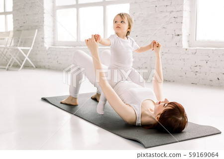 Young sporty mother and baby girl do exercises together in the gym. Parent and child healthy 59169064