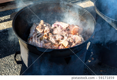 Pieces of meat cooking in a large cauldron Pieces of meat cooking in a large cauldron 59171859