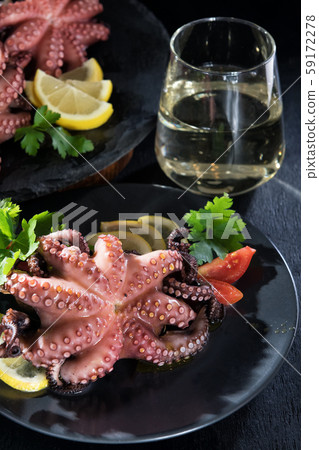 Stuffed octopus in white wine with lemon cooked in the oven on a black background. Atmospheric wonderful rich romantic dinner with sparkling white wine Stuffed octopus in white wine with lemon cooked in the oven on a black background. Atmospheric wonderful rich romantic dinner with sparkling white wine 59172278