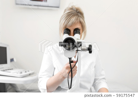 Female blond doctor gynecologist looks through a 59175547