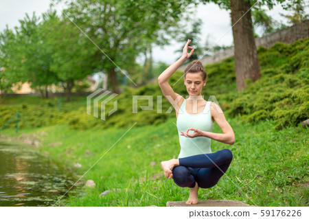 A young sports girl practices yoga on a green lawn A young sports girl practices yoga on a green lawn 59176226