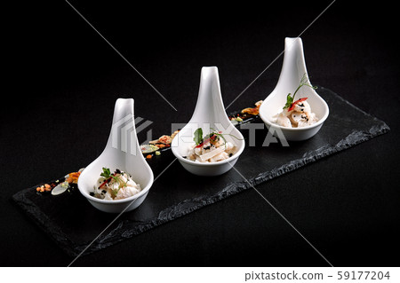 Sea bass ceviche mini portions served in beautiful Chinese spoons on a black plateau. Food concept Sea bass ceviche mini portions served in beautiful Chinese spoons on a black plateau. Food concept 59177204