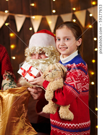 Child girl accepting gifts from Santa near 59177653