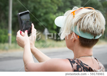 Adult blonde woman makes selfie on a smartphone on 59178981