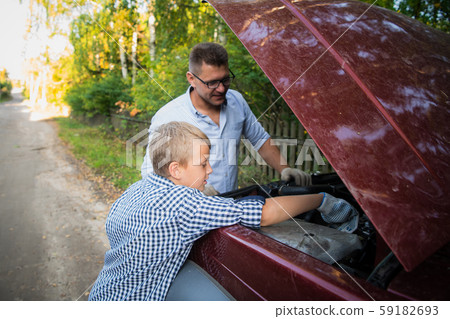 Father teaching his son how to check the oil on the family car. 59182693