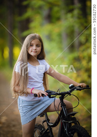 Cute little teenager girl riding bicycle in a sunny park Cute little teenager girl riding bicycle in a sunny park 59182730